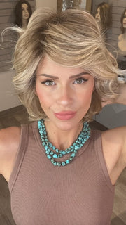 Madeline wearing MONROE by BELLETRESS in BUTTERCAKE BLONDE-R | A neutral-warm blonde blend featuring light brown, ash, and lightest blonde tones with natural-looking darker roots for added depth and realism.