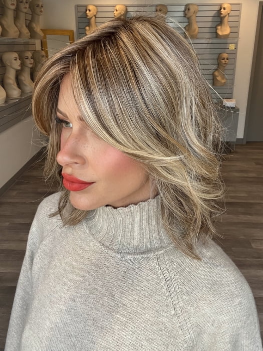 Madeline wearing CYRUS by BELLETRESS in BROWN SUGAR BLONDE-R | A warm, dimensional blend of medium brown and golden blonde highlights with natural-looking darker roots for depth and a sun-kissed finish.