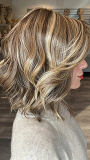 Madeline wearing CYRUS by BELLETRESS in BROWN SUGAR BLONDE-R | A warm, dimensional blend of medium brown and golden blonde highlights with natural-looking darker roots for depth and a sun-kissed finish.