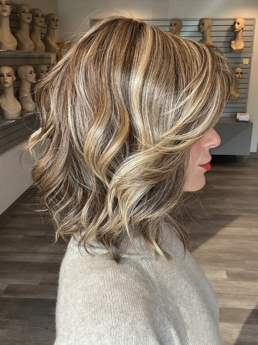 Madeline wearing CYRUS by BELLETRESS in BROWN SUGAR BLONDE-R | A warm, dimensional blend of medium brown and golden blonde highlights with natural-looking darker roots for depth and a sun-kissed finish.