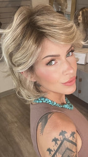 Madeline wearing MONROE by BELLETRESS in BUTTERCAKE BLONDE-R | A neutral-warm blonde blend featuring light brown, ash, and lightest blonde tones with natural-looking darker roots for added depth and realism.