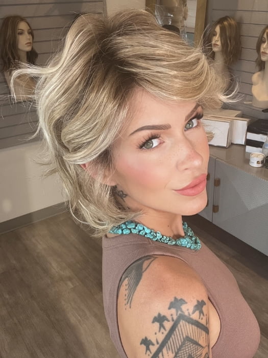 Madeline wearing MONROE by BELLETRESS in BUTTERCAKE BLONDE-R | A neutral-warm blonde blend featuring light brown, ash, and lightest blonde tones with natural-looking darker roots for added depth and realism.