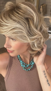 Madeline wearing MONROE by BELLETRESS in BUTTERCAKE BLONDE-R | A neutral-warm blonde blend featuring light brown, ash, and lightest blonde tones with natural-looking darker roots for added depth and realism.