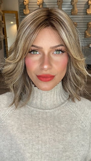 Madeline wearing CYRUS by BELLETRESS in BROWN SUGAR BLONDE-R | A warm, dimensional blend of medium brown and golden blonde highlights with natural-looking darker roots for depth and a sun-kissed finish.
