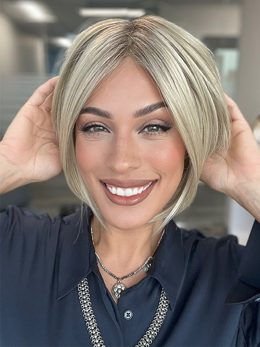 Model is wearing AYUMI by NORIKO in color Light Ash Blond R | Cream Ash Blonde with ash brown and white-grey roots that blend into a variety of ash blonde tones, including ash pearl blonde, creamy ivory, and pale cream