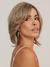 Model is wearing SHEENA by RENE OF PARIS in color CHAMPAGNE SUNSET | Dark/medium multi-tonal blond with textured honey, ash, and golden hues and chocolate brown roots
