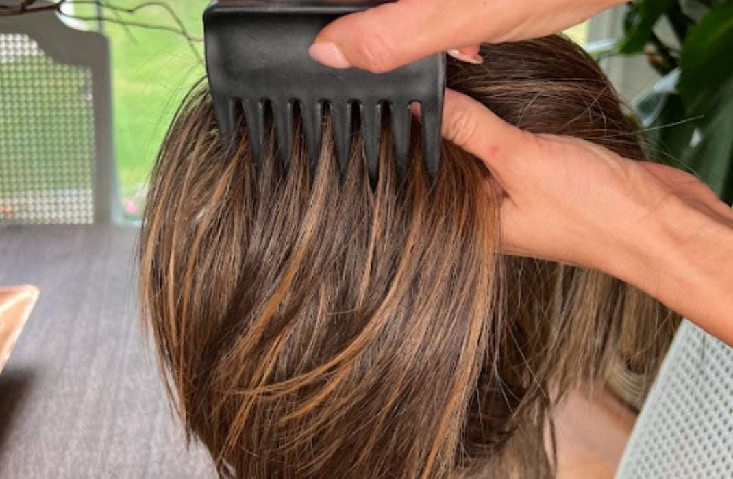 A wig being combed with a wide toothed comb
