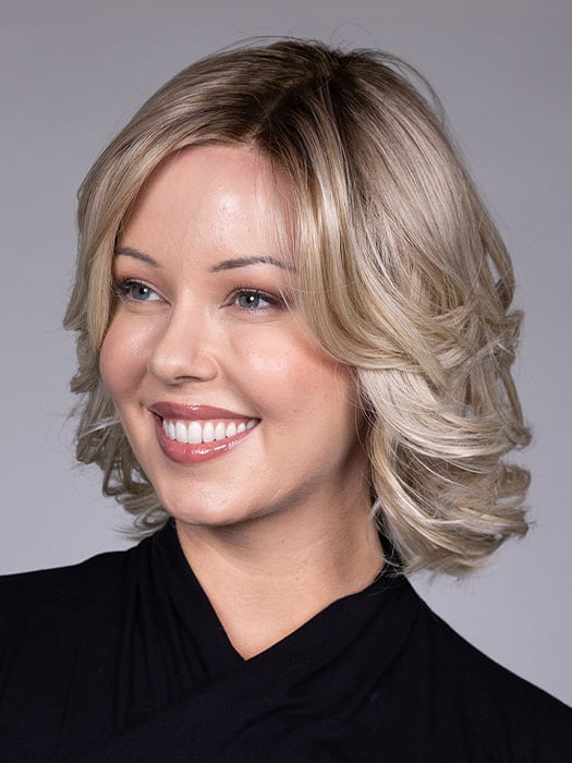 Model is wearing HELSINKI by BELLETRESS in color CRUSHED ALMOND BLONDE R | A soft Neutral Light Blonde with a Light and Medium Blended Root Color.