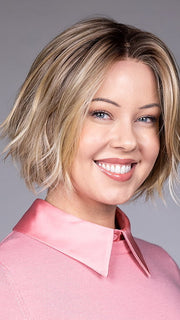 Model is wearing OSLO by BELLETRESS in color RAW SUGAR BLONDE | A Neutral Light Blonde, Honey Blonde, Pale Gold Blonde, with a base of Light Brown Lowlights featuring a Medium Root Color