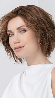 Model is wearing JADORE DELUXE by ELLEN WILLE in color CHOCOLATE-ROOTED | Medium to Dark Brown base with Light Reddish Brown highlights and Dark Roots