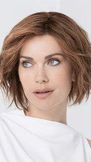 Model is wearing JADORE DELUXE by ELLEN WILLE in color CHOCOLATE-ROOTED | Medium to Dark Brown base with Light Reddish Brown highlights and Dark Roots